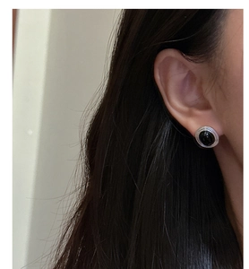 Close-up of vintage S925 silver stud earrings with black onyx worn on a woman's ear