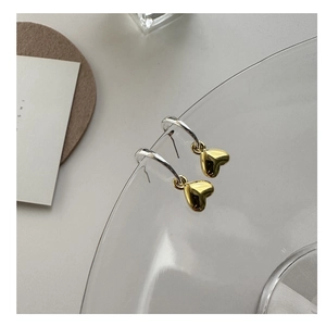 Dettaglio di orecchini a cerchio in argento con ciondoli a cuore in oro lucido