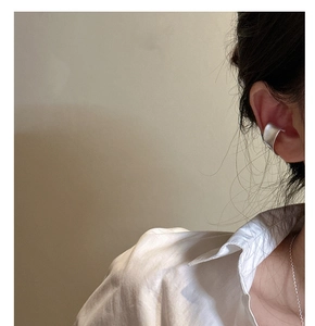 Gros plan sur un clip d'oreille minimaliste en argent mat sur une oreille de modèle