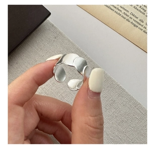Detail of matte S925 silver open ring with layered petal texture on a finger
