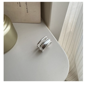 Détail d'une bague double couche en argent S925 mat sur un fond minimaliste