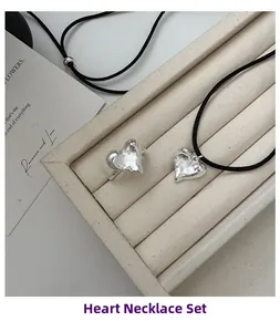 Dettaglio macro del set gioielli cuore argento con anello materico e collana nera