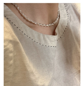 Gros plan d'un collier chaîne torsadée en argent sterling 925 sur une chemise en lin