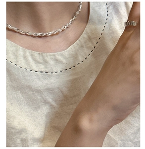 Gros plan sur le collier en argent S925 et la bague large au style minimaliste épuré