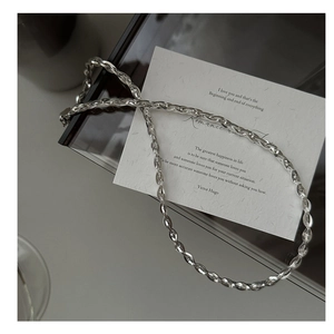 Vue détaillée d'un collier chaîne serpent en argent sur un fond de carte épuré