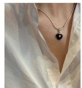 Close-up of minimalist black heart pendant on a delicate S925 silver chain necklace