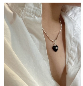 Close-up of S925 silver necklace with black heart pendant on a white shirt model