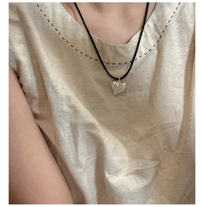 Dettaglio della collana con ciondolo a cuore in argento e cordino nero su modella