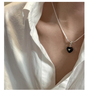 Close-up of S925 sterling silver necklace with black heart pendant on a model in white shirt
