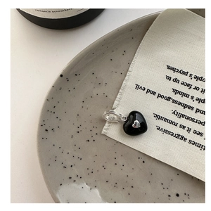 Detail of a S925 silver heart pendant with black enamel finish on a rustic fabric background