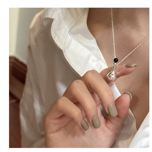 Close-up of S925 silver necklace with perfume bottle pendant and black bead on woman