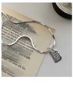 Macro detail of silver rectangular pendant with Live in the moment engraved message