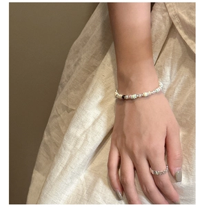 Detail of colorful beaded bracelet and silver geometric ring on warm fabric