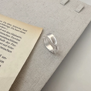 Minimalist S925 sterling silver knotted ring with matte brushed finish on woven board