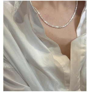 Detail view of the silver irregular stone chain necklace on a white shirt