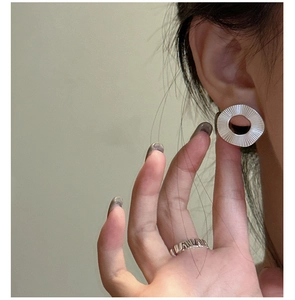 Détail de boucles d'oreilles rondes plissées en argent S925 avec texture radiale sur mannequin
