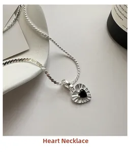 Macro detail of S925 silver heart necklace featuring a black zircon and textured chain