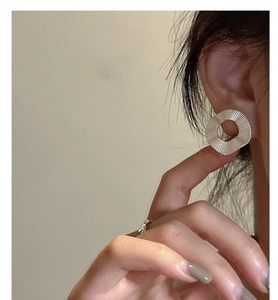 Gros plan de boucles d'oreilles en argent S925 avec texture géométrique plissée sur l'oreille