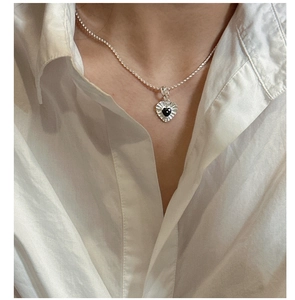 Detail of silver S925 heart pendant with black zircon on model wearing white shirt