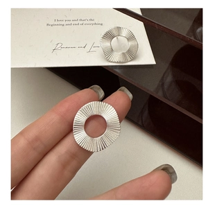 Gros plan de boucles d'oreilles en argent S925 avec plis radiaux et design rond ajouré
