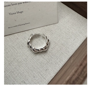 Close-up of S925 sterling silver croissant twisted ring on a rustic linen background