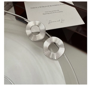Détail des boucles d'oreilles rondes en argent S925 avec texture plissée soleil