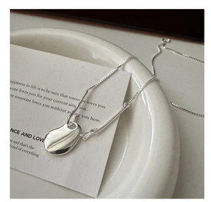 Close-up of minimalist S925 sterling silver irregular teardrop necklace on a ceramic plate