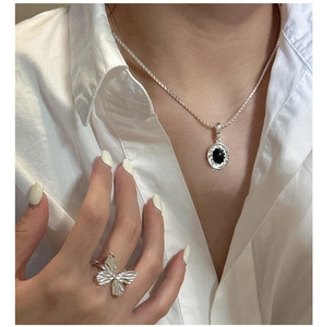 Detail of silver S925 necklace with black onyx pendant and butterfly shaped ring on model