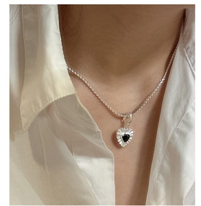 Close-up of minimalist S925 silver necklace with black heart pendant on a model