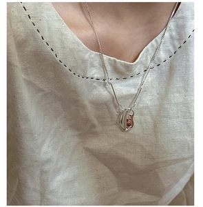 Close-up of minimalist silver water-drop pendant on a delicate chain necklace