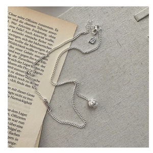 Detail of S925 sterling silver necklace with engraved ball pendant on vintage book background