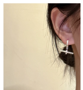 Gros plan de boucles d'oreilles barre en T en argent S925 portées au lobe de l'oreille