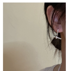 Détail de boucles d'oreilles minimalistes en argent avec barre en T portées par un mannequin