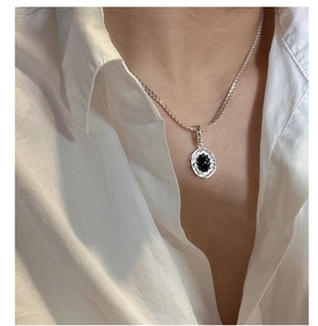 Detail view of S925 silver necklace featuring a black onyx wavy pendant on a model