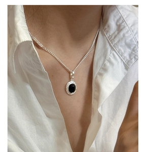 Close-up of S925 sterling silver necklace with black agate pendant on a white collar