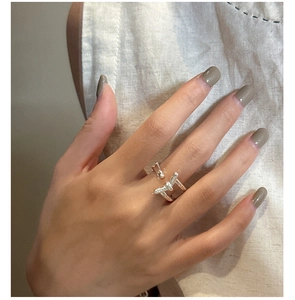 Detailed close-up of a silver knot ring with a sleek twisted design on a finger