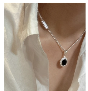 Close-up of S925 sterling silver necklace with black agate pendant on white shirt