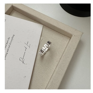 Macro shot of S925 sterling silver ring with irregular geometric texture on cream fabric