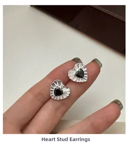 Close-up of S925 silver heart stud earrings with black zircon and pleated metal texture