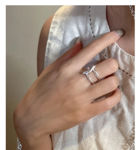 Macro detail of a S925 sterling silver double-band ring with a central knot design on hand