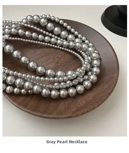 Macro d'un collier de perles grises lustrées de tailles variées sur plateau en bois