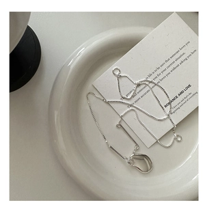 Macro detail of silver fluid organic ring pendant on delicate box chain jewelry