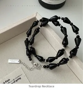 Detail of s925 silver necklace with black agate beads and engraved metal tag