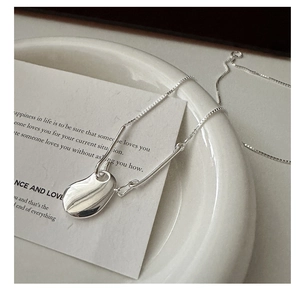 Macro shot of silver S925 fluid bean pendant on fine box chain with mirror finish