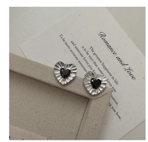 Detail of silver heart stud earrings with pleated texture and black zircon center stone