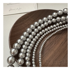 Détail macro de divers colliers de perles gris argent S925 sur un plateau en bois chic