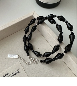 Macro detail of teardrop black onyx beads necklace with adjustable silver chain and tag