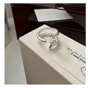 Detailed close-up of a silver knot ring on a beige linen display box for jewelry