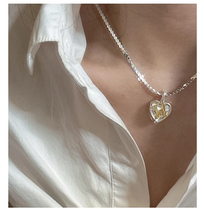 Close-up of heart pendant necklace with gold H initial on silver base and rope chain