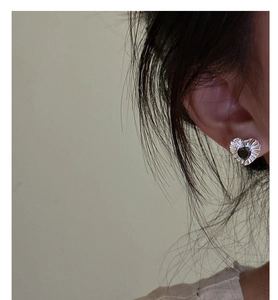 Close-up of S925 silver heart stud earrings with black zircon and textured radial engraving